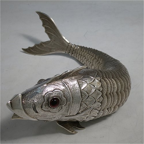 A rare Antique Victorian Silver large articulated fish, with hand engraved and chased body having  articulated scales, a hinged mouth and face with cabochon garnet eyes, with a tail fin, dorsal fin, and sitting on two lower pelvic fins. Made in ca. 1890 in mainland Continental Europe (possibly Spain). The dimension of this fine hand-made antique silver fish model are length 30.5 cms (12 inches), and it weighs approx. 283g (9 troy ounces).