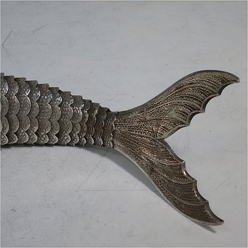 A rare Antique Victorian Silver large articulated fish, with hand engraved and chased body having  articulated scales, a hinged mouth and face with cabochon garnet eyes, with a tail fin, dorsal fin, and sitting on two lower pelvic fins. Made in ca. 1890 in mainland Continental Europe (possibly Spain). The dimension of this fine hand-made antique silver fish model are length 30.5 cms (12 inches), and it weighs approx. 283g (9 troy ounces).