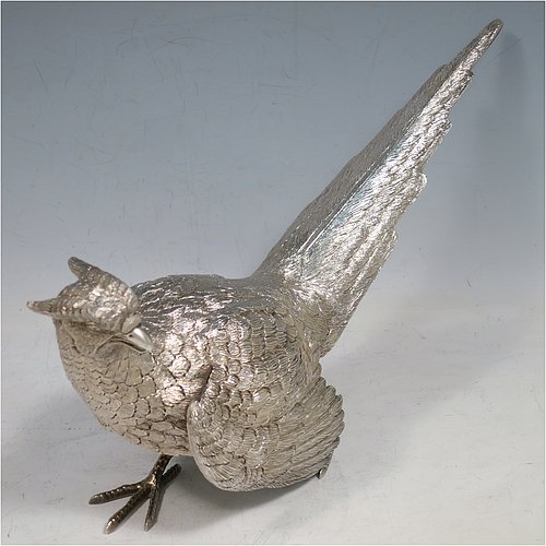 A Sterling Silver large pair of cast pheasants, showing a male and female bird in realistic traditional poses, finely detailed with hand-chased bodies and tail feathers. Made by C. J. Vanders of London in 2000. The dimensions of these fine hand-made sterling silver pheasants are length of male bird 28 cms (11 inches), height 17 cms (6.75 inches), and they weigh a total approx. 1,945g (63 troy ounces).   