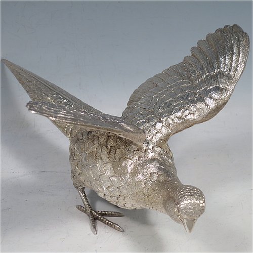 A Sterling Silver large pair of cast pheasants, showing a male and female bird in realistic traditional poses, finely detailed with hand-chased bodies and tail feathers. Made by C. J. Vanders of London in 2000. The dimensions of these fine hand-made sterling silver pheasants are length of male bird 28 cms (11 inches), height 17 cms (6.75 inches), and they weigh a total approx. 1,945g (63 troy ounces).   