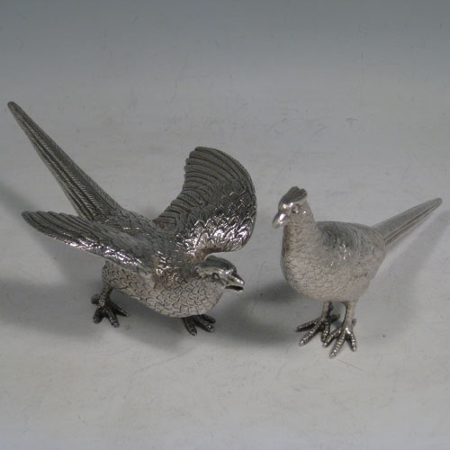 Sterling silver pair of cast pheasants, showing two male cock birds, with realistically hand-chased feathers. Made by A.E. Jones of Birmingham in 1975. The dimensions of these sterling silver pheasants are: length of startled bird out 16.5 cms (6.5 inches), height of resting bird 8 cms (3 inches), width of startled bird 10 cms (4 inches). Weight approx. 483g (15.6 troy ounces).   