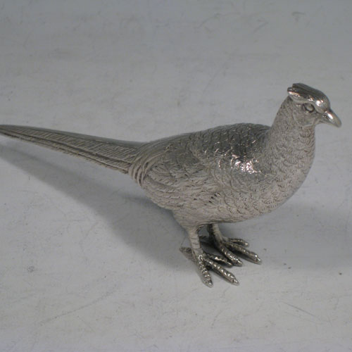 Sterling silver pair of cast pheasants, showing two male cock birds, with realistically hand-chased feathers. Made by A.E. Jones of Birmingham in 1975. The dimensions of these sterling silver pheasants are: length of startled bird out 16.5 cms (6.5 inches), height of resting bird 8 cms (3 inches), width of startled bird 10 cms (4 inches). Weight approx. 483g (15.6 troy ounces).   