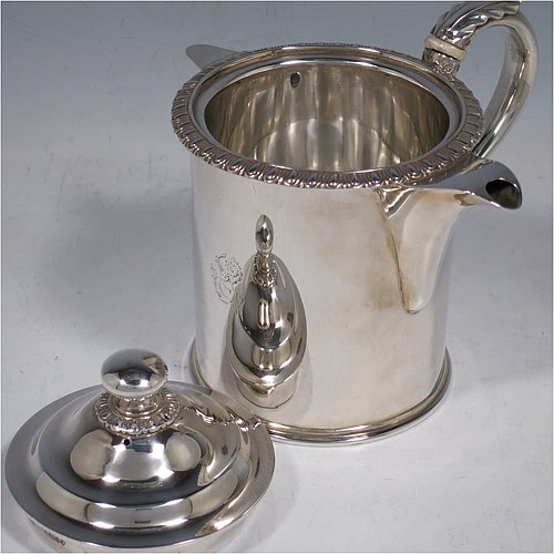 An Antique Victorian Sterling Silver Argyll, having a plain round body with straight sides and an applied gadroon border, a pull-off lid with ball finial, a sparrow-beak spout, a scroll handle with anthemion leaf thumb-piece and bone insulation, a separate side spout with hinged lid for adding hot water to the water jacket, and sitting on a flat base. Made by Thomas Henry & Frederick Francis of London in 1861. The dimensions of this fine hand-made antique silver Argyll are height 12.5 cms (5 inches), diameter 9 cms (3.5 inches), and it weighs approx. 465g (15 troy ounces). Please note that this item is crested.