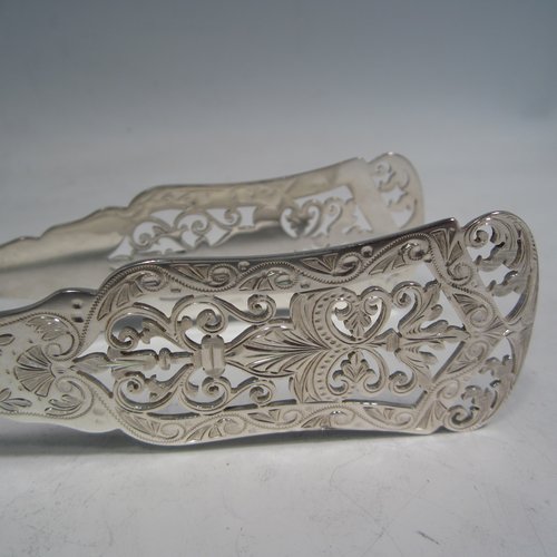 An Antique Victorian sterling silver Old English Thread pattern pair of pretty asparagus serving tongs, having hand-pierced blades with floral decoration, and original retaining guard with screw. Made by Edward Hutton of London in 1892. The dimensions of this fine pair of antique silver asparagus servers are length 24 cms (9.5 inches), and they weigh approx. 151g (4.9 troy ounces).   