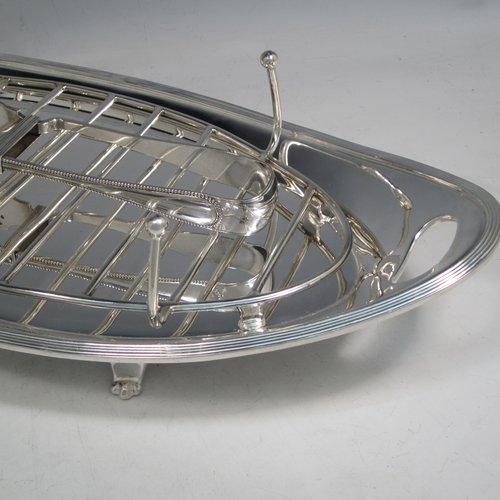 Antique Edwardian silver plated asparagus serving set, having a plain oval body, with an applied reeded border, an original wire-work serving rack, two cut-out side-handles, and sitting on four cast flange feet. Together with a matching pair of tongs made by John Grinsell of Sheffield in ca. 1900. The dimensions of this fine hand-made silver-plated asparagus serving set are length 43 cms (17 inches), and width, 21.5 cms (8.5 inches).   