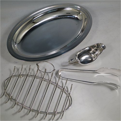 A Silver Plated asparagus serving set, having a plain oval body, with an applied rounded border, an original wire-work serving rack, a pair of plain serving tongs, and a sauce boat sat in a frame with loop handle, and all sitting on a flat base. Made by Deakin & Frances of Sheffield in ca. 1920. The dimensions of this fine hand-made silver-plated asparagus serving set are length 30.5 cms (12 inches), and width, 19.5 cms (7.75 inches).   