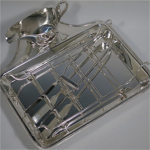 An Antique Edwardian Silver Plated asparagus serving set, having a plain rectangular body, with an applied gadroon border, a wire-work serving rack, a sauce boat sat in a frame with loop handle, a pair of asparagus server tongs, and all sitting on a base with four cast trefoil feet. All pieces were made by Mappin and Webb of London in ca. 1900. The dimensions of this fine hand-made antique silver-plated asparagus serving set are length 26.5 cms (10.5 inches), and width, 25.5 cms (10 inches).    