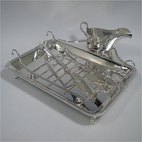 An Antique Edwardian Silver Plated asparagus serving set, having a plain rectangular body, with an applied gadroon border, a wire-work serving rack, a sauce boat sat in a frame with loop handle, a pair of asparagus server tongs, and all sitting on a base with four cast trefoil feet. All pieces were made by Mappin and Webb of London in ca. 1900. The dimensions of this fine hand-made antique silver-plated asparagus serving set are length 26.5 cms (10.5 inches), and width, 25.5 cms (10 inches).    