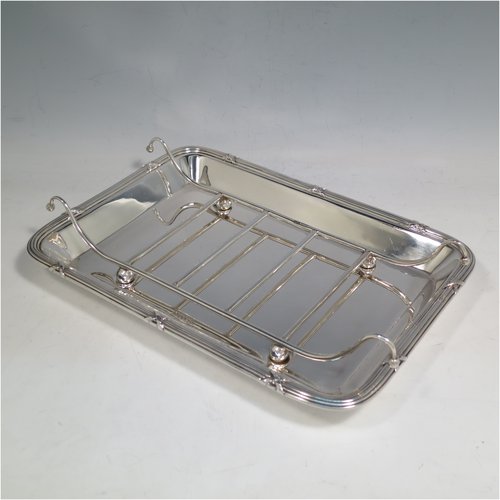 An Antique Edwardian Sterling Silver asparagus serving set, having a plain rectangular body with rounded corners, an applied Ribbon & Reed border, an original wire-work serving rack, and all sitting on a base with four cushion feet. Made by Mappin & Webb of Sheffield in 1909. The dimensions of this fine hand-made antique silver asparagus serving set are length 27 cms (10.5 inches), and width, 19 cms (7.5 inches), and it weighs approx. 727g (23.5 troy ounces).