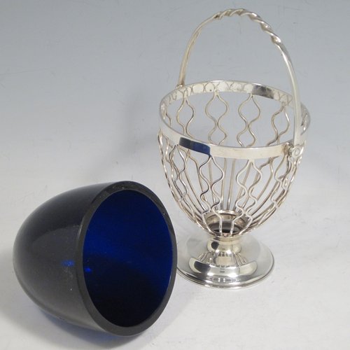 Antique Edwardian sterling silver sweet-meat basket, having a round tapering wire-work body, a  hinged and twisted swing handle, sitting on a plain round pedestal foot, and with an original blue-glass liner. Made by Hukin & Heath of Birmingham in 1902. The dimensions of this fine hand-made silver sweet-meat basket are height inc. handle 15 cms (6 inches), diameter at lip 8.5 cms (3.3 inches), and it weighs approx. 128g (4 troy ounces).   