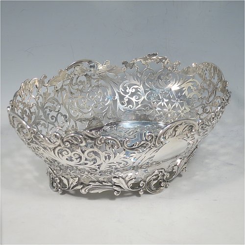 An Antique Victorian Sterling Silver table basket, having an oval hand-pierced body with very pretty floral decoration, with cast floral & scroll  borders, and sitting on four cast floral and scroll feet. Made by James Dixon & Sons of Sheffield in 1901. The dimensions of this fine hand-made antique silver basket are length 21 cms (8.25 inches), width 16 cms (6.25 inches), height 8 cms (3.25 inches), and it weighs approx. 356g (11.5 troy ounces).   