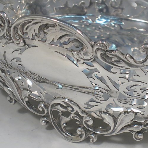 An Antique Victorian Sterling Silver table basket, having an oval hand-pierced body with very pretty floral decoration, with cast floral & scroll  borders, and sitting on four cast floral and scroll feet. Made by James Dixon & Sons of Sheffield in 1901. The dimensions of this fine hand-made antique silver basket are length 21 cms (8.25 inches), width 16 cms (6.25 inches), height 8 cms (3.25 inches), and it weighs approx. 356g (11.5 troy ounces).   