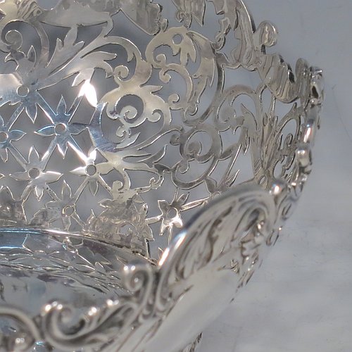 An Antique Victorian Sterling Silver table basket, having an oval hand-pierced body with very pretty floral decoration, with cast floral & scroll  borders, and sitting on four cast floral and scroll feet. Made by James Dixon & Sons of Sheffield in 1901. The dimensions of this fine hand-made antique silver basket are length 21 cms (8.25 inches), width 16 cms (6.25 inches), height 8 cms (3.25 inches), and it weighs approx. 356g (11.5 troy ounces).   