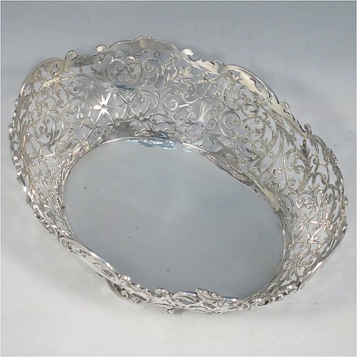 An Antique Victorian Sterling Silver table basket, having an oval hand-pierced body with very pretty floral decoration, with cast floral & scroll  borders, and sitting on four cast floral and scroll feet. Made by James Dixon & Sons of Sheffield in 1901. The dimensions of this fine hand-made antique silver basket are length 21 cms (8.25 inches), width 16 cms (6.25 inches), height 8 cms (3.25 inches), and it weighs approx. 356g (11.5 troy ounces).   