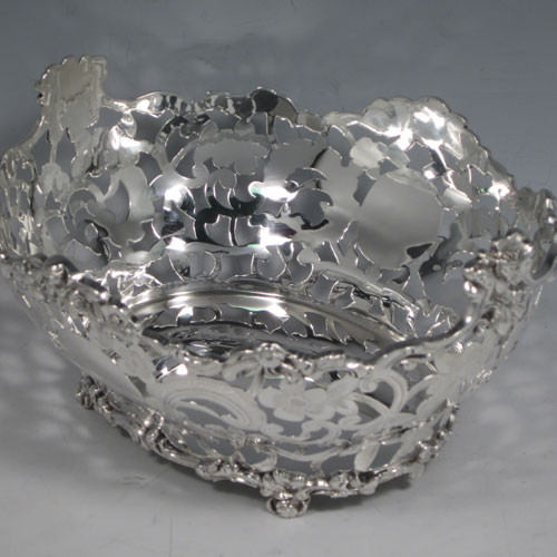 Antique Victorian sterling silver table basket, having an oval hand-pierced and engraved body with floral decoration, with cast floral borders, and sitting on four cast floral feet. Made by D. & J. Wellby of London in 1901. The dimensions of this fine hand-made silver basket are length 18 cms (7 inches), width 16 cms (6.25 inches), height 9 cms (3.5 inches), and it weighs approx. 336g (10.8 troy ounces).