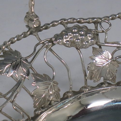 An Antique Georgian Sterling Silver sweet-meat basket with swing-handle, having wire-work decoration with applied grape-vines and leaves, a shaped rope-twist border, a hinged twisted handle, and all sitting on a plain collet foot. Made by Edward Aldridge of London in 1760. The dimensions of this fine hand-made antique silver sweetmeat basket are length 16 cms (6.3 inches), width 13 cms (5 inches), height 13 cms (5 inches), and it weighs approx. 155g (5 troy ounces).   