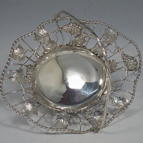 An Antique Georgian Sterling Silver sweet-meat basket with swing-handle, having wire-work decoration with applied grape-vines and leaves, a shaped rope-twist border, a hinged twisted handle, and all sitting on a plain collet foot. Made by Edward Aldridge of London in 1760. The dimensions of this fine hand-made antique silver sweetmeat basket are length 16 cms (6.3 inches), width 13 cms (5 inches), height 13 cms (5 inches), and it weighs approx. 155g (5 troy ounces).   