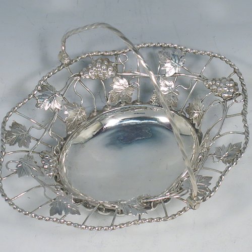 An Antique Georgian Sterling Silver sweet-meat basket with swing-handle, having wire-work decoration with applied grape-vines and leaves, a shaped rope-twist border, a hinged twisted handle, and all sitting on a plain collet foot. Made by Edward Aldridge of London in 1760. The dimensions of this fine hand-made antique silver sweetmeat basket are length 16 cms (6.3 inches), width 13 cms (5 inches), height 13 cms (5 inches), and it weighs approx. 155g (5 troy ounces).   