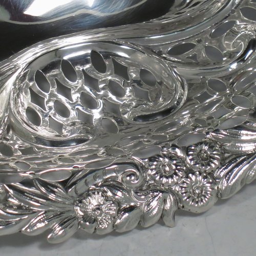 An Antique Edwardian pair of Sterling silver table baskets, having oval bodies with hand-pierced scroll-work decoration, with hand-chased floral borders, and sitting on matching pierced & scroll feet. Made by Charles Boyton of London in 1902. The dimensions of this fine pair of antique silver baskets are length 27 cms (10.75 inches), width 18.5 cms (7.25 inches), height 9 cms (3.5 inches), and they weigh a total of approx. 586g (19 troy ounces).   