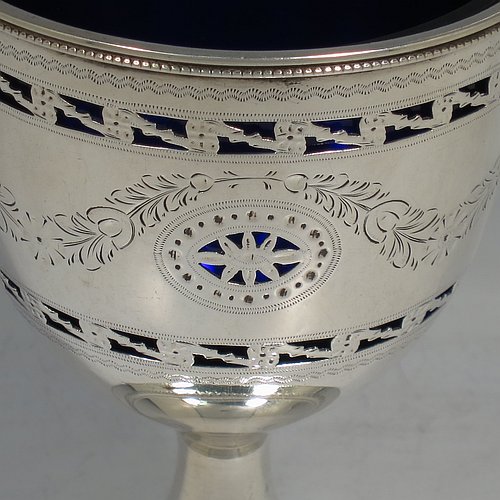 An Antique Edwardian Sterling Silver sweet-meat basket, having a round body with tapering sides all hand-engraved and hand-pierced with neoclassical style decoration, a hinged swing handle with applied bead-work, sitting on a round pedestal foot, and with an original blue-glass liner. Made by Thomas Bradbury of London in 1902. The dimensions of this fine hand-made antique silver sweet-meat basket are height inc. handle 16 cms (6.25 inches), diameter at lip 8.5 cms (3.3 inches), and it weighs approx. 140g (4.5 troy ounces).    