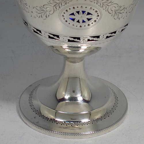 An Antique Edwardian Sterling Silver sweet-meat basket, having a round body with tapering sides all hand-engraved and hand-pierced with neoclassical style decoration, a hinged swing handle with applied bead-work, sitting on a round pedestal foot, and with an original blue-glass liner. Made by Thomas Bradbury of London in 1902. The dimensions of this fine hand-made antique silver sweet-meat basket are height inc. handle 16 cms (6.25 inches), diameter at lip 8.5 cms (3.3 inches), and it weighs approx. 140g (4.5 troy ounces).    