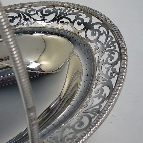 A very pretty Antique Victorian Sterling Silver basket, having an oval body with an applied gadroon border, all hand-pierced with floral and scroll decoration, a hinged swing handle, and all sitting on an oval stepped pedestal foot. Made by J.H. and H. Barraclough of London in 1899. The dimensions of this fine hand-made antique silver basket are height 21 cms (8.25 inches), length 26.5 cms (10.5 inches), width 20 cms (8 inches), and it weighs approx. 548g (17.7 troy ounces).    