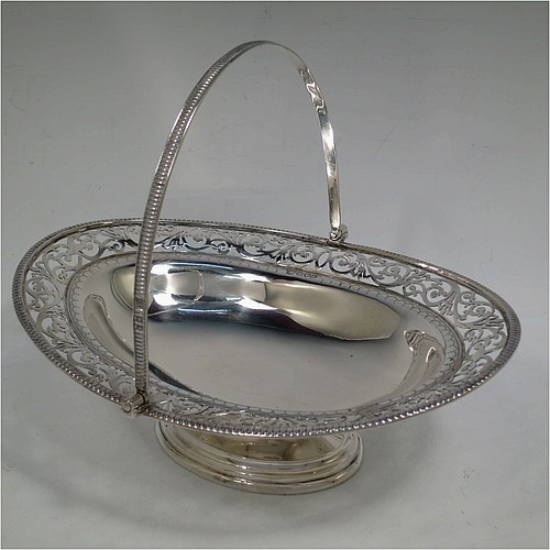 A very pretty Antique Victorian Sterling Silver basket, having an oval body with an applied gadroon border, all hand-pierced with floral and scroll decoration, a hinged swing handle, and all sitting on an oval stepped pedestal foot. Made by J.H. and H. Barraclough of London in 1899. The dimensions of this fine hand-made antique silver basket are height 21 cms (8.25 inches), length 26.5 cms (10.5 inches), width 20 cms (8 inches), and it weighs approx. 548g (17.7 troy ounces).    