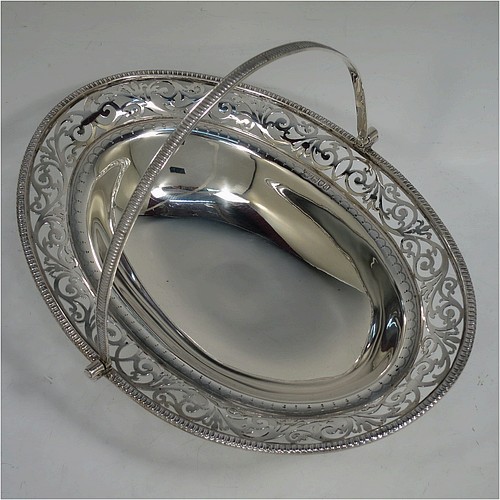 A very pretty Antique Victorian Sterling Silver basket, having an oval body with an applied gadroon border, all hand-pierced with floral and scroll decoration, a hinged swing handle, and all sitting on an oval stepped pedestal foot. Made by J.H. and H. Barraclough of London in 1899. The dimensions of this fine hand-made antique silver basket are height 21 cms (8.25 inches), length 26.5 cms (10.5 inches), width 20 cms (8 inches), and it weighs approx. 548g (17.7 troy ounces).    