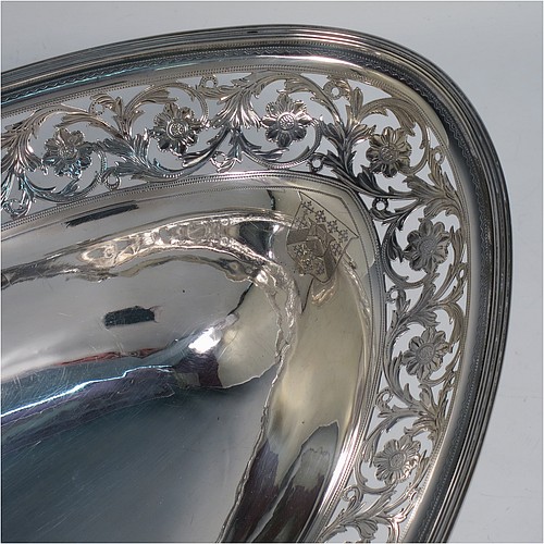 A very pretty Antique Georgian Sterling Silver basket, having an oval body with an applied reeded border, with an upper band of hand-engraved and hand-pierced floral work, a hinged and reeded swing handle, all sitting on a geometrically hand-pierced collet foot. Made by Thomas Harper I of London in 1796. The dimensions of this fine hand-made antique silver basket are height 28 cms (11 inches), length 37 cms (14.5 inches), width 26 cms (10.25 inches), and it weighs approx. 792g (25.5 troy ounces). Please note that this basket is crested.