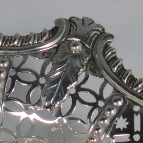 An Antique Georgian Sterling Silver basket, having an oval body with an applied shaped gadroon border, with hand-pierced panels separated by bands of bead-work, a hinged swing handle, and all sitting on a a matching pierced foot. Made by Edward Aldridge of London in 1767. The dimensions of this fine hand-made antique silver basket are height 25 cms (9.75 inches), length 37 cms (14.5 inches), width 31 cms (12.25 inches), and it weighs approx. 900g (29 troy ounces).