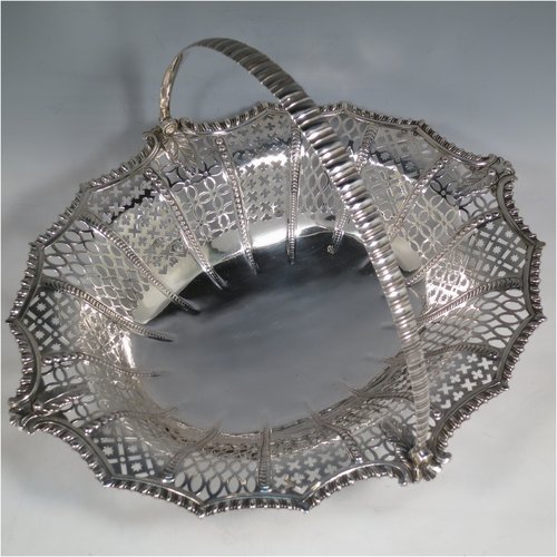 An Antique Georgian Sterling Silver basket, having an oval body with an applied shaped gadroon border, with hand-pierced panels separated by bands of bead-work, a hinged swing handle, and all sitting on a a matching pierced foot. Made by Edward Aldridge of London in 1767. The dimensions of this fine hand-made antique silver basket are height 25 cms (9.75 inches), length 37 cms (14.5 inches), width 31 cms (12.25 inches), and it weighs approx. 900g (29 troy ounces).