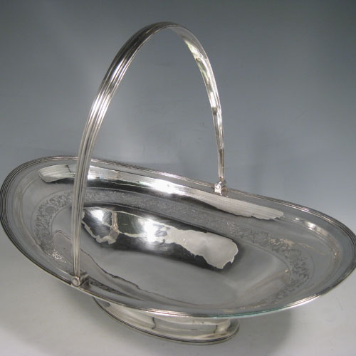 Antique Georgian sterling silver basket, having an oval body with an applied reeded edge, with a band of hand-engraved floral work and acorns, a hinged and reeded swing handle, all sitting on a collet foot. Made in London in 1800. The dimensions of this hand-made silver basket are height 27 cms (10.5 inches), length 35.5 cms (14 inches), width 23.5 cms (9.5 inches), and it weighs approx. 687g (22 troy ounces). Please note that although the hallmarks are rubbed the date letter E is evident. 