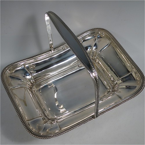 An Antique Edwardian Sterling Silver basket, having a rectangular body, with an applied gadroon border, a hinged and swing handle with gadroon edges, all sitting on a pedestal foot. Made by the Dixon Brothers of Sheffield in 1910. The dimensions of this fine hand-made antique silver basket are height 23 cms (9 inches), length 27.5 cms (10.75 inches), width 21 cms (8.25 inches), and it weighs approx. 746g (24 troy ounces).    