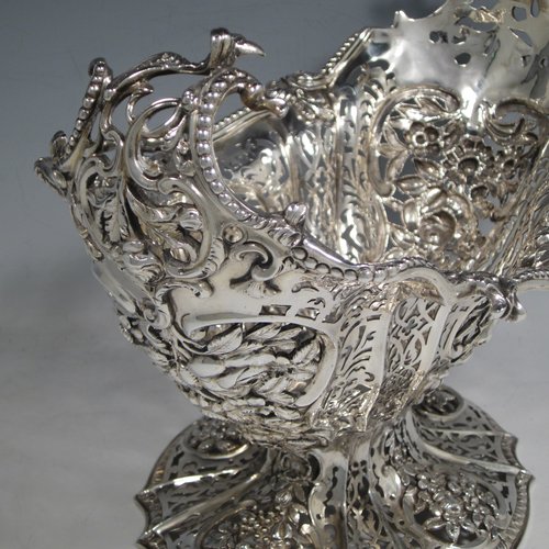 Antique Victorian large sterling silver table basket, in an asymmetrical Art Nouveau style, having an oval hand-pierced body with hand-chased floral decoration, with cast floral and bead-edged borders, and sitting on a matching pedestal foot. Made by Martin Hall & Co., of Sheffield in 1892. The dimensions of this fine hand-made silver basket are length 27.5 cms (10.75 inches), width 23 cms (9 inches), height 21.5 cms (8.5 inches), and it weighs approx. 1,100g (35.5 troy ounces).   