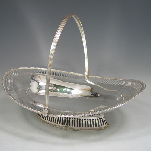 Antique Georgian sterling silver basket, having an oval body with an applied bead edge, a hand-pierced border, with bands of hand-engraved floral work, a hinged and reeded swing handle, all sitting on a hand-pierced collet foot. Made by John Deaken of London in 1777. Height 25.5 cms (10 inches), length 34 cms (13.5 inches), width 25 cms (10 inches). Weight approx. 722g (23.3 troy ounces).