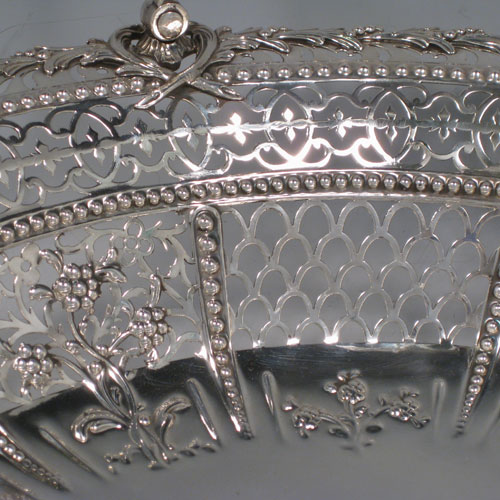 Antique Georgian sterling silver hand-pierced basket with swing-handle, having bands of floral piercing divided by hand-chased bead-work, an applied cast floral border, a cast floral swing-handle, and sitting on a pierced collet foot with rope-twist border. Made by Richard Mills of London in 1772. The dimensions of this fine hand-made silver basket are length 30.5 cms (12 inches), width 27.5 cms (10.75 inches), height 28 cms (11 inches), and it weighs approx. 937g (30 troy ounces).