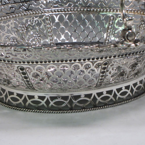 Antique Georgian sterling silver hand-pierced basket with swing-handle, having bands of floral piercing divided by hand-chased bead-work, an applied cast floral border, a cast floral swing-handle, and sitting on a pierced collet foot with rope-twist border. Made by Richard Mills of London in 1772. The dimensions of this fine hand-made silver basket are length 30.5 cms (12 inches), width 27.5 cms (10.75 inches), height 28 cms (11 inches), and it weighs approx. 937g (30 troy ounces).