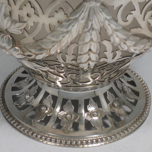 Antique Victorian sterling silver sweetmeat basket, having a round hand-pierced and chased body with floral decoration bead-edged borders, loop and knot handle, frosted glass liner, and sitting on a pierced pedestal foot. Made by the William Savory of London in 1863. Height including handle 18 cms (7 inches), diameter 13 cms (5 inches). Weight approx. 267g (8.6 troy ounces).