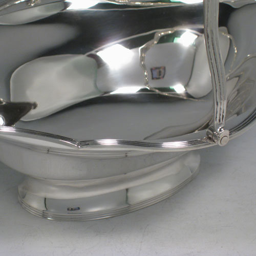 An elegant Antique Edwardian Sterling Silver table basket, having a plain oval body with shaped border and applied reeded edge, a hinged reeded handle, and sitting on a collet foot with reeded border. This handsome silver basket was made by Charles Stuart Harris of London in 1903. The dimensions of this fine hand-made antique silver basket are height inc. handle 20 cms (8 inches), length 23 cms (9 inches), 19 cms (7.5 inches), and it weighs approx. 339g (11 troy ounces).   