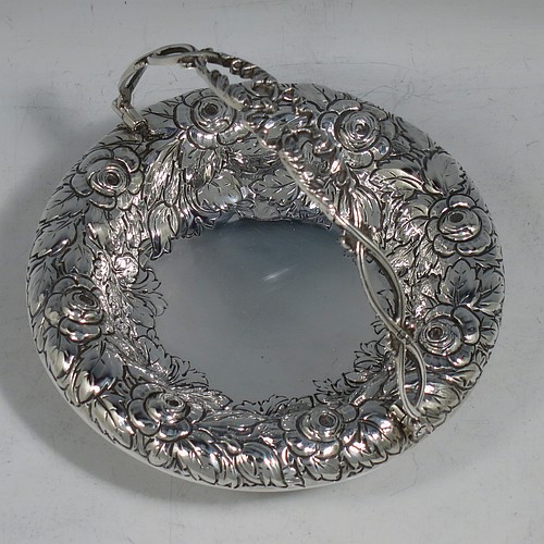 An Antique Victorian Sterling Silver sweet-meat basket, having a round body with hand-chased floral decoration, a hinged hand-pierced and chased swing handle, and all sitting on a plain round pedestal foot. Made by Henry Wilkinson & Co., of London in 1893. The dimensions of this fine hand-made antique silver basket are height 10 cms (4 inches), diameter 12.5 cms (5 inches), and it weighs approx. 147g (4.7 troy ounces).   