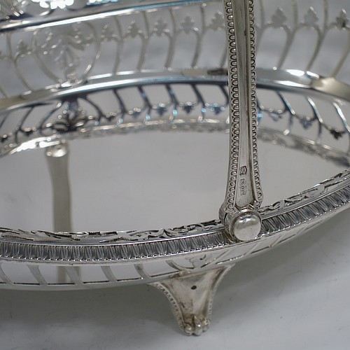 A very pretty Sterling Silver basket, having an oval body with an applied gadroon border, all hand-pierced with floral and scroll decoration, a hinged and pierced swing handle, and all sitting on four cast flange feet. Made by James Dixon and Sons of Sheffield in 1927. The dimensions of this fine hand-made silver basket are height 20 cms (8 inches), length 28 cms (11 inches), width 20 cms (8 inches), and it weighs approx. 548g (17.7 troy ounces).   