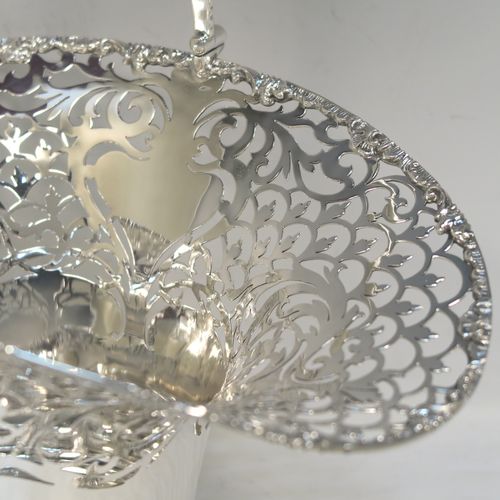 A large and very pretty Antique Edwardian Sterling Silver wedding style basket, having a round body with applied floral borders and hand-pierced floral and scroll decoration, a matching swing handle, and all sitting on a pedestal foot. This beautiful silver wedding basket was made by Jackson and Fullerton of London in 1907. The dimensions of this fine hand-made antique silver wedding basket are height 31 cms (12.25 inches), length 27 cms (10.75 inches), width 20 cms (8 inches), and it weighs approx. 633g (20.4 troy ounces).  