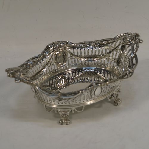 A very pretty Neoclassical style Antique Edwardian Sterling silver small table basket, having an oval body with hand-pierced decoration and hand-chased floral borders, all sitting on four cast lions-paw feet. This beautiful antique silver basket was made by Goldsmiths and Silversmiths of London in 1909. The dimensions of this fine antique silver basket are length 17 cms (6.75 inches), width 11 cms (4.3 inches), height 7 cms (2.75 inches), and it weighs approx. 227g (7.3 troy ounces).   