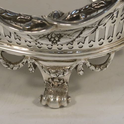 A very pretty Neoclassical style Antique Edwardian Sterling silver small table basket, having an oval body with hand-pierced decoration and hand-chased floral borders, all sitting on four cast lions-paw feet. This beautiful antique silver basket was made by Goldsmiths and Silversmiths of London in 1909. The dimensions of this fine antique silver basket are length 17 cms (6.75 inches), width 11 cms (4.3 inches), height 7 cms (2.75 inches), and it weighs approx. 227g (7.3 troy ounces).   