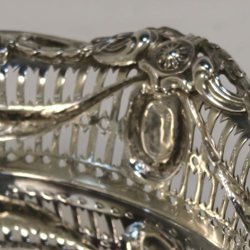 A very pretty Neoclassical style Antique Edwardian Sterling silver small table basket, having an oval body with hand-pierced decoration and hand-chased floral borders, all sitting on four cast lions-paw feet. This beautiful antique silver basket was made by Goldsmiths and Silversmiths of London in 1909. The dimensions of this fine antique silver basket are length 17 cms (6.75 inches), width 11 cms (4.3 inches), height 7 cms (2.75 inches), and it weighs approx. 227g (7.3 troy ounces).   