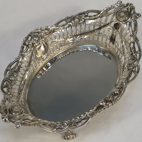 A very pretty Neoclassical style Antique Edwardian Sterling silver small table basket, having an oval body with hand-pierced decoration and hand-chased floral borders, all sitting on four cast lions-paw feet. This beautiful antique silver basket was made by Goldsmiths and Silversmiths of London in 1909. The dimensions of this fine antique silver basket are length 17 cms (6.75 inches), width 11 cms (4.3 inches), height 7 cms (2.75 inches), and it weighs approx. 227g (7.3 troy ounces).   