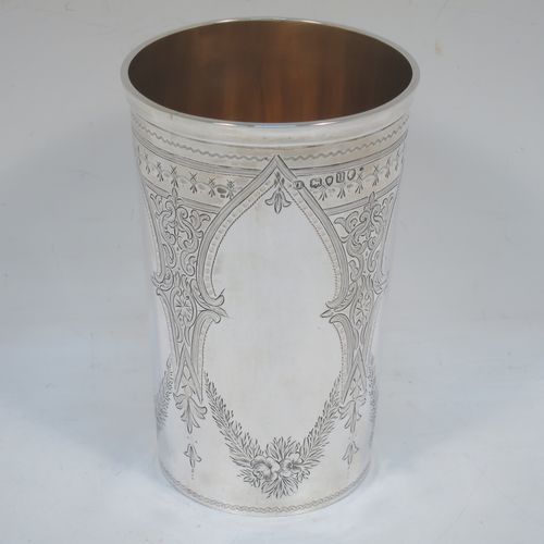 A very pretty and large Antique Victorian Sterling Silver beaker, having a round straight-sided body with tapering sides, with hand-engraved scroll and floral decoration  surrounding four vacant cartouches, a gold-gilt interior, and all sitting on a flat base. Made by William Evans of London in 1875. The dimensions of this fine hand-made antique silver beaker are height 12.5 cms (5 inches), diameter at top 8 cms (3 inches), and it weighs approx. 170g (5.5 troy ounces).   