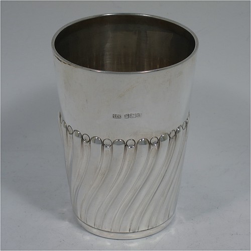 A very handsome Antique Edwardian Sterling Silver beaker, having a round straight-sided body with tapering sides, hand-chased work with half-swirl fluted decoration, with a gold-gilt interior, and all sitting on a flat base. Made by Henry Atkins of Sheffield in 1902. The dimensions of this fine hand-made antique silver beaker are height 10 cms (4 inches), diameter at top 7 cms (2.75 inches), and it weighs approx. 124g (4 troy ounces). 