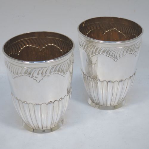 A very pretty Antique Victorian Sterling Silver pair of beaker cups, having round bodies with tapering sides and hand-chased fluted decoration, god-gilt interiors, and sitting on a collet feet. Made by H. J. Lias and J. Wakely of London in 1882. The dimensions of this fine pair of hand-made antique silver beakers are height 10.5 cms (4.25 inches), diameter at top 8 cms (3.25 inches), and they weigh a total of approx. 282g (9 troy ounces).  