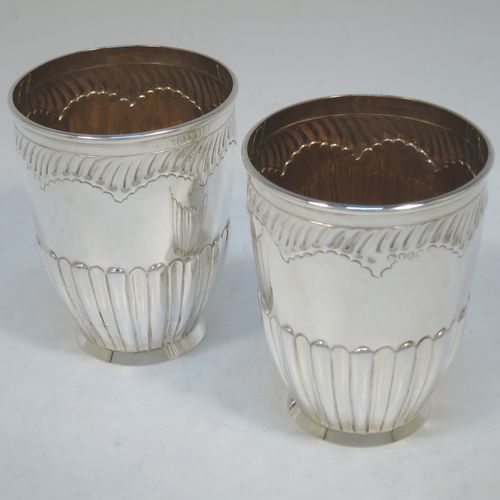 A very pretty Antique Victorian Sterling Silver pair of beaker cups, having round bodies with tapering sides and hand-chased fluted decoration, god-gilt interiors, and sitting on a collet feet. Made by H. J. Lias and J. Wakely of London in 1882. The dimensions of this fine pair of hand-made antique silver beakers are height 10.5 cms (4.25 inches), diameter at top 8 cms (3.25 inches), and they weigh a total of approx. 282g (9 troy ounces).  